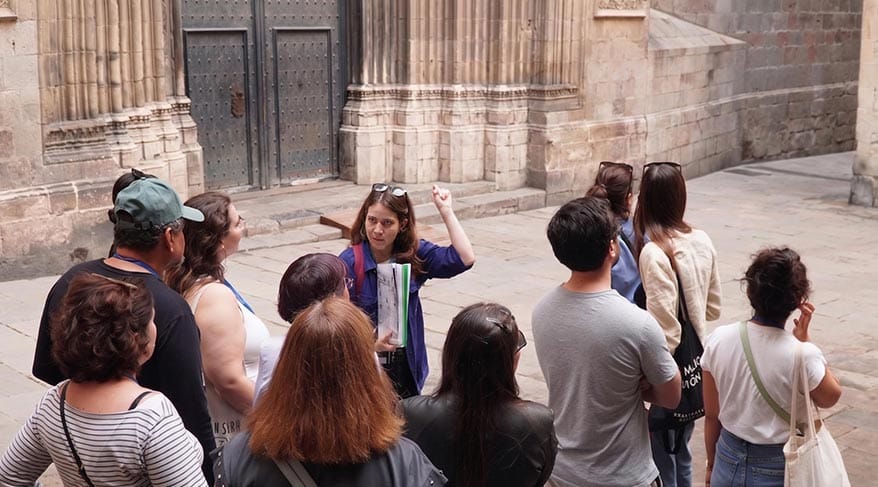 Guía explicando la historia del Barrio Gótico de Barcelona a un grupo de personas durante un tour cultural