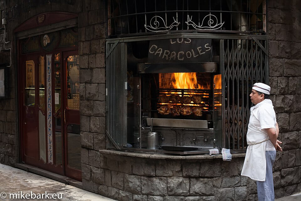 Entrada del histórico restaurante Los Caracoles, en el Barrio Gótico de Barcelona, conocido por su cocina tradicional y su parrilla visible desde la calle, uno de los establecimientos más emblemáticos de la ciudad.