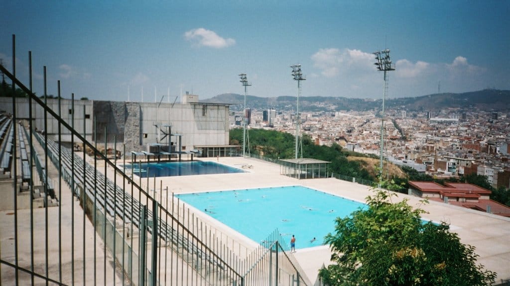 Vista de la Piscina Olímpica de Montjuïc en Barcelona, con las plataformas de saltos y la ciudad al fondo.