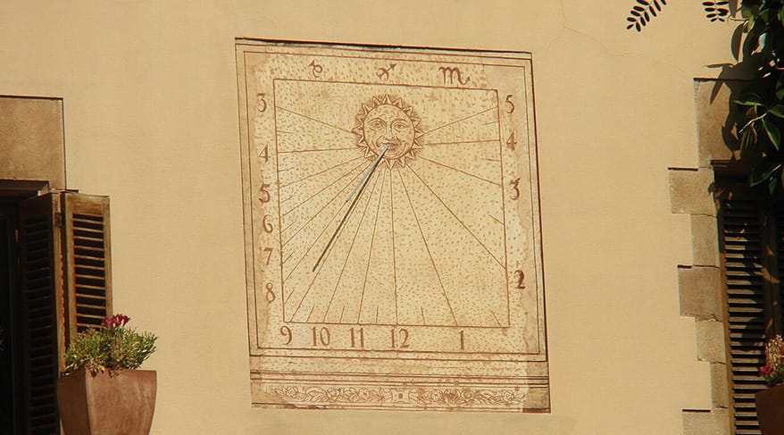 Reloj de sol decorativo en una fachada de Barcelona, Cataluña, fotografiado a plena luz del día.